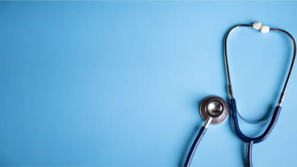 Stethoscope placed on a light blue background with empty space on the left.